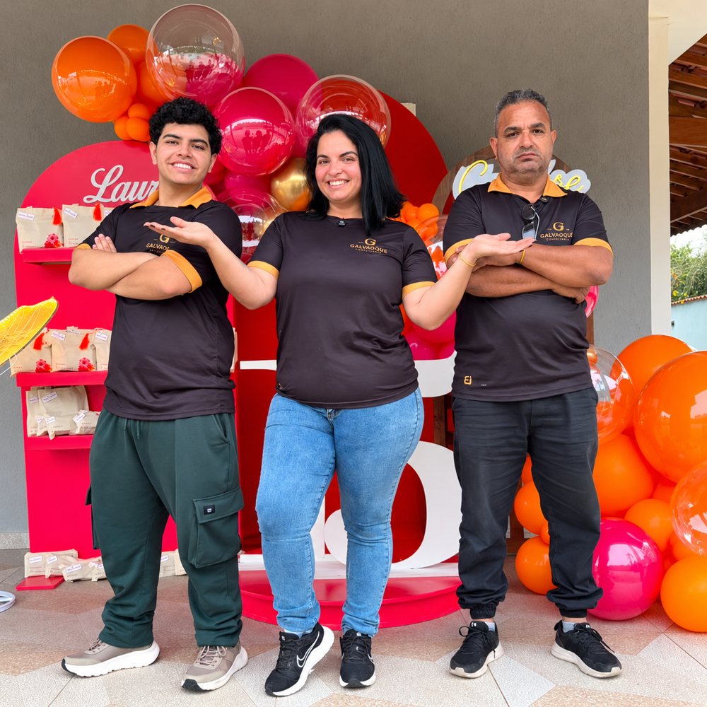 A equipe da Galvaques, com a camisa da empresa, na frente de uma decoração de balões laranja e pink